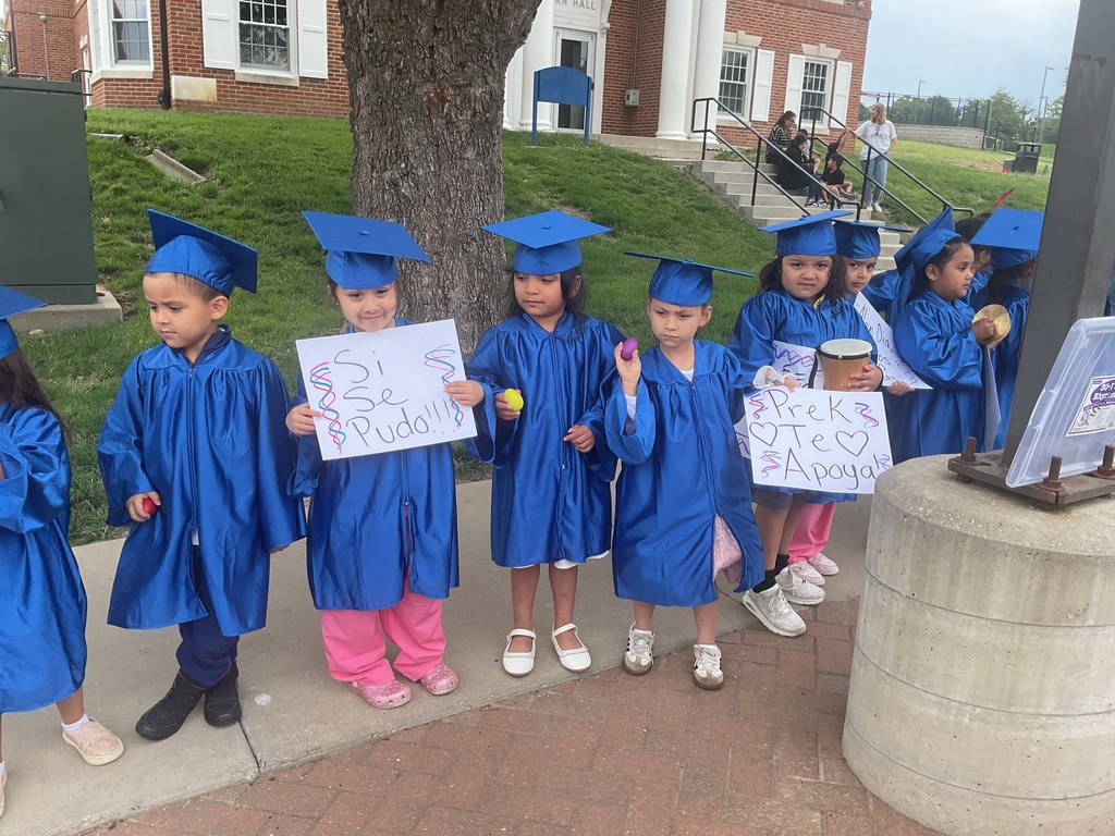 PK students wearing a gown holding signs.