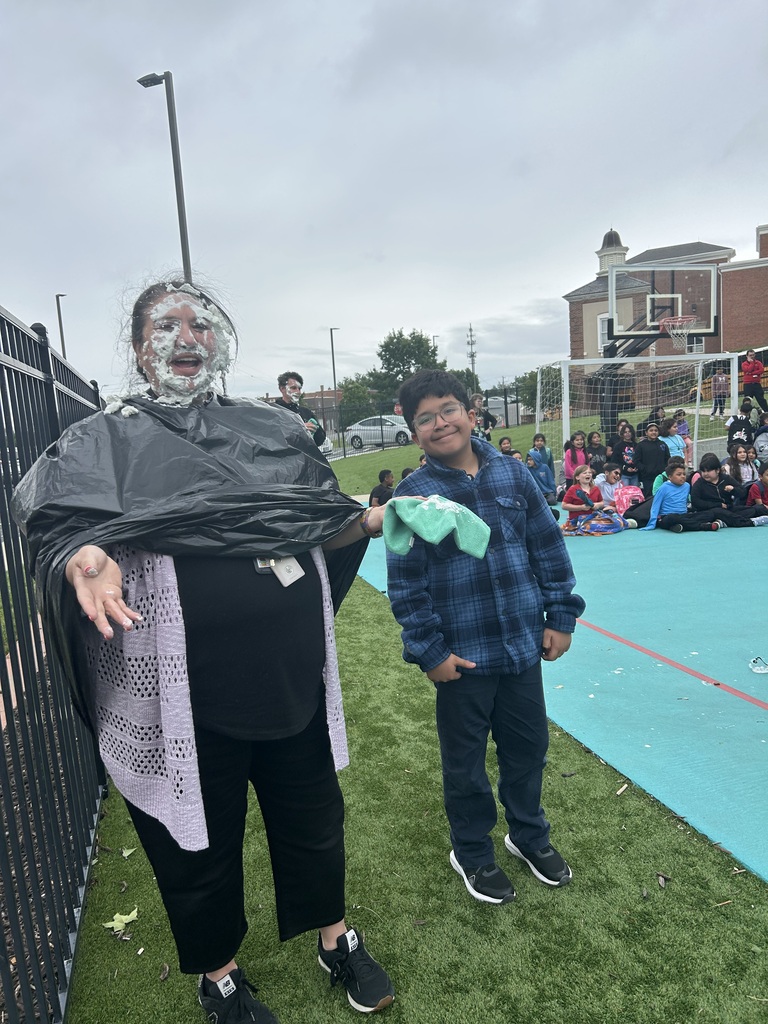 Student holding a plate and female teacher with cream on face posing for the camera