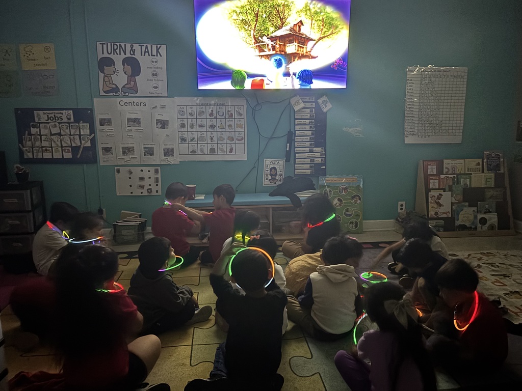 kids sitting on the floor watching a movie with glow sticks