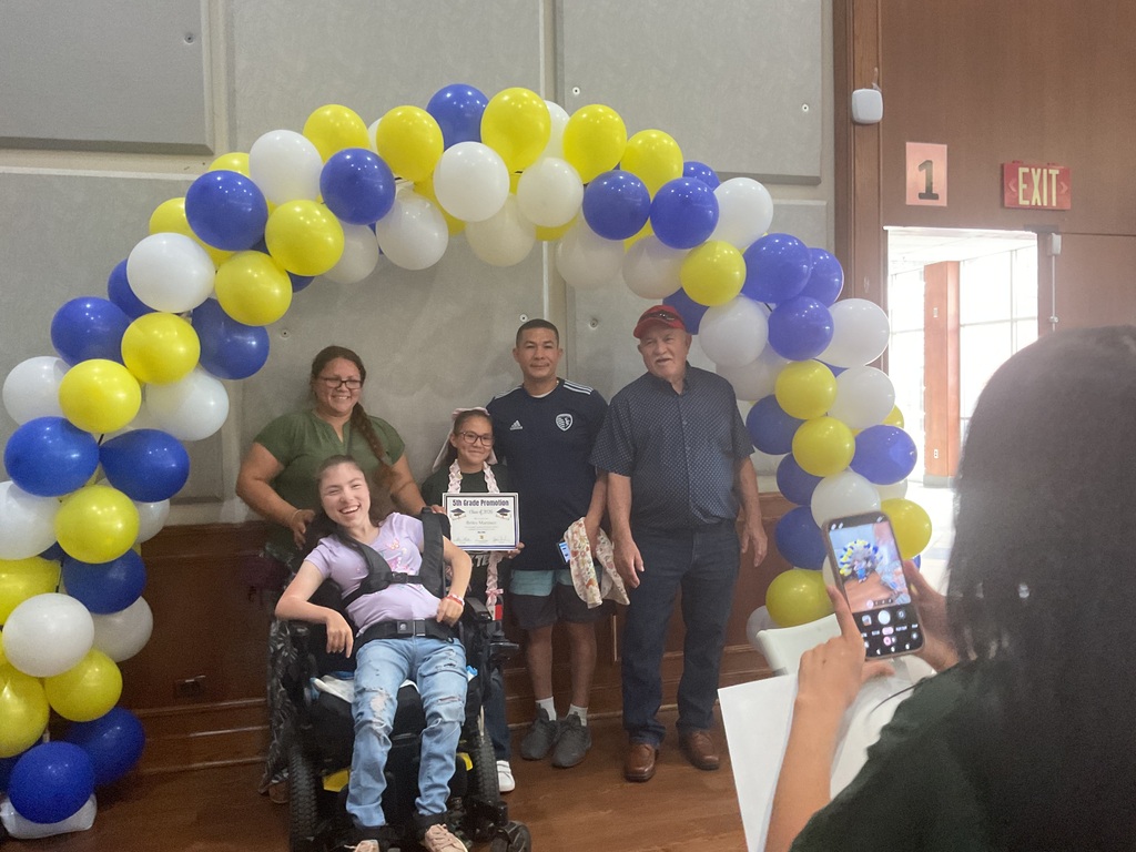 A family under a balloon arch posing for a picture