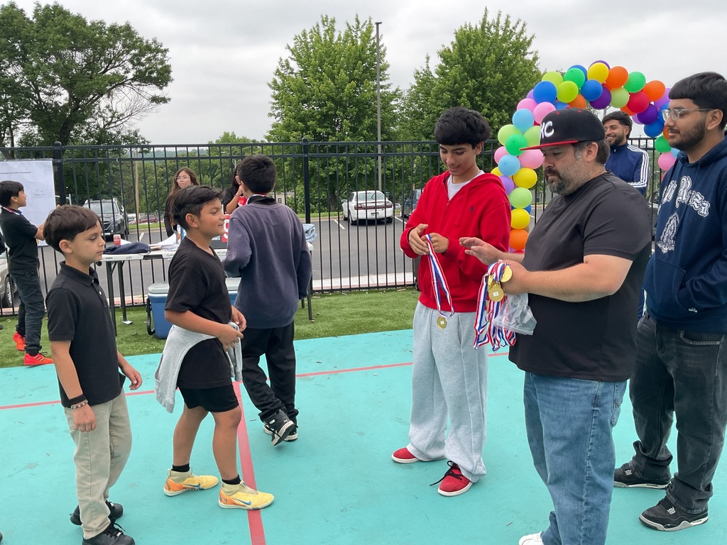 2 adults giving medals to 2 students