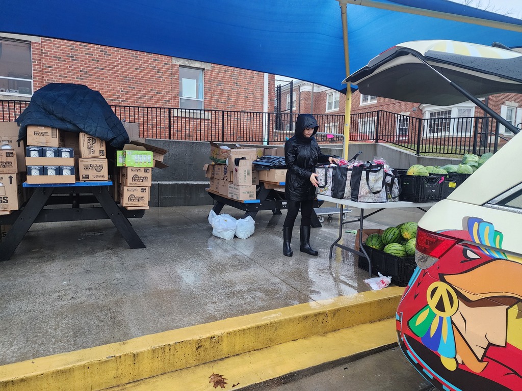 A female volunteer is helping organize and arrange food pantry items that will be distributed to families. She carefully sorts and stacks the donated food supplies, preparing them for fair and orderly distribution.