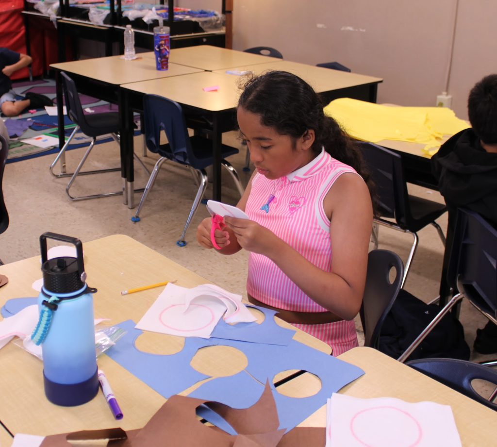 2nd grader cutting out peices of paper