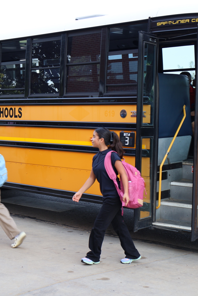 student wearing pink backpack getting off the bus