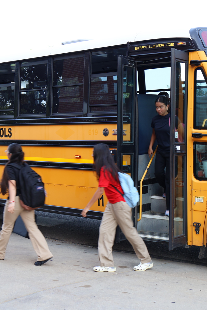student in red shirt and blue backpack getting off the bus 