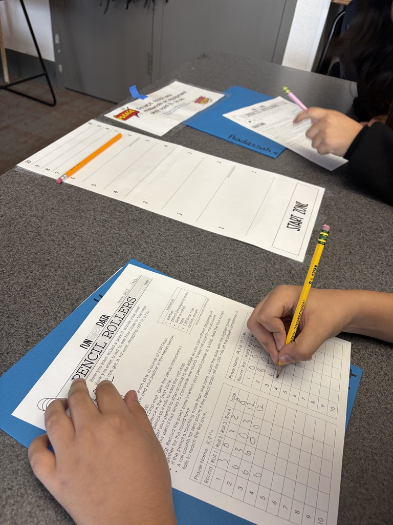 student holding a pencil and writing on their paper, recording their data