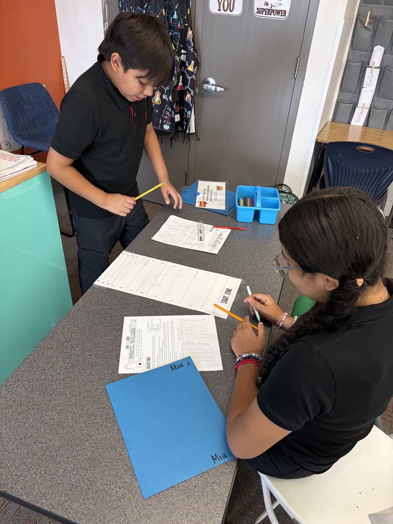 two students working on their lab while holding their pencils