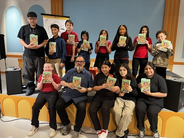 students from Guadalupe Centers middle school posing with Pedro Martin and holding up his book. 