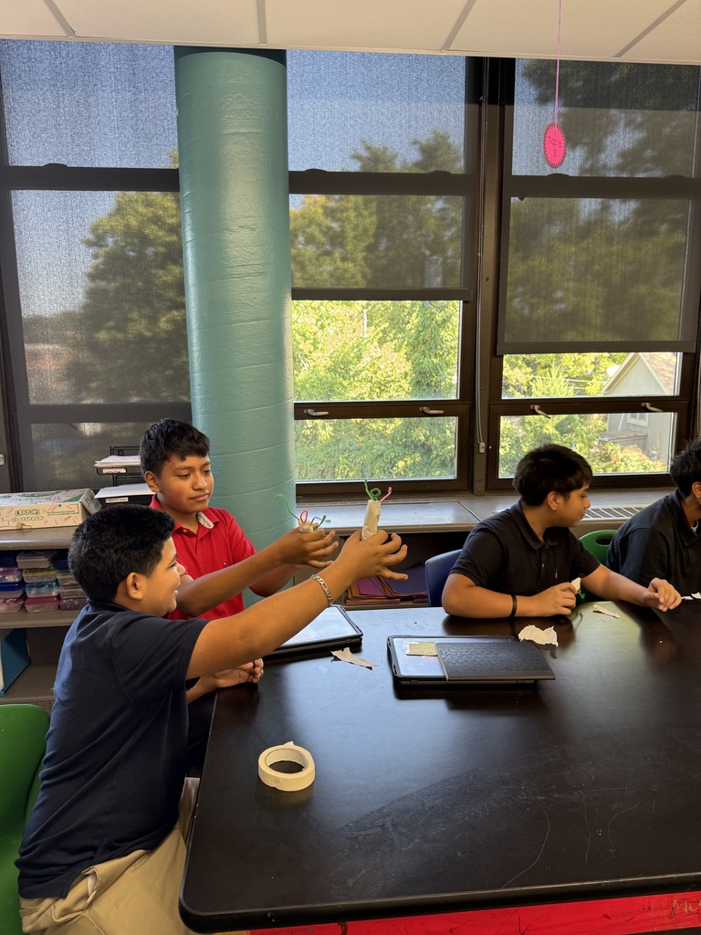 students sitting at a black table showing each other their 3D characters