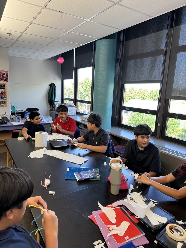 students sitting at a table socializing and working with each other 