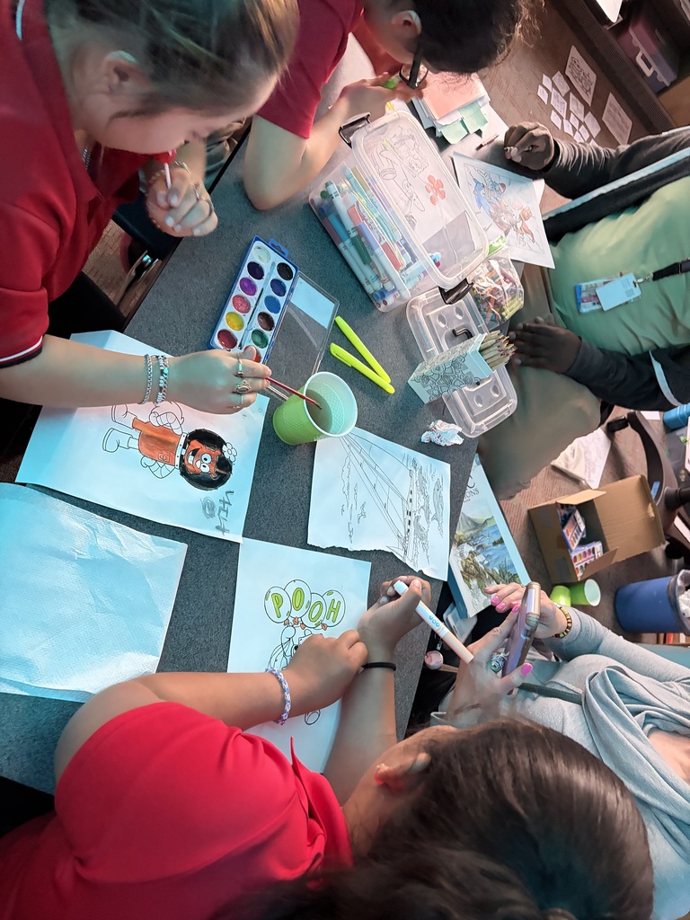 students in red uniform shirts painting on a white sheet paper on the table.
