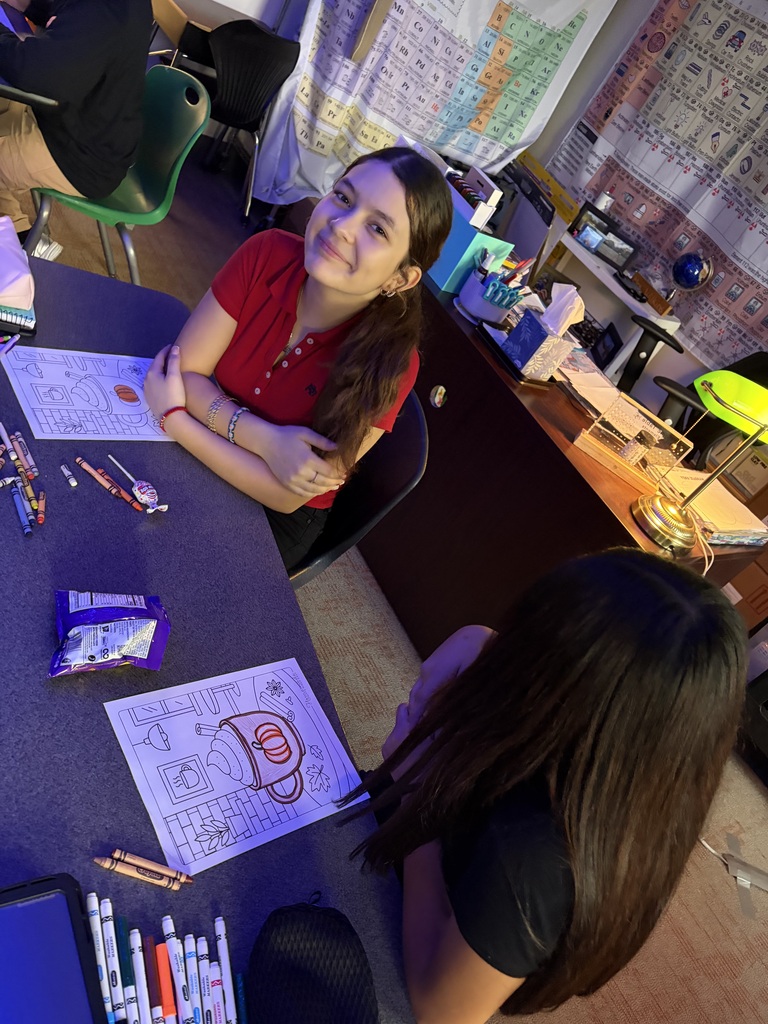 student in a red polo smiling and leaning against the table 