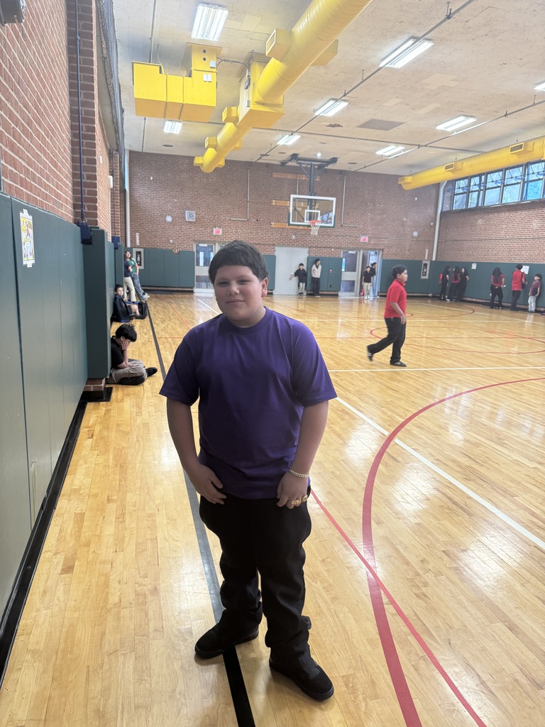 student wearing purple shirt and black pants standing in the gym posing for a picture