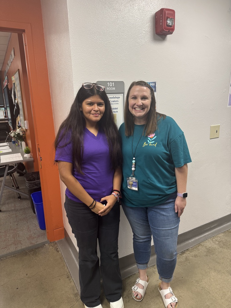 student in purple shirt and black pants and teacher wearing jeans and teal shirt, posing for a picture.