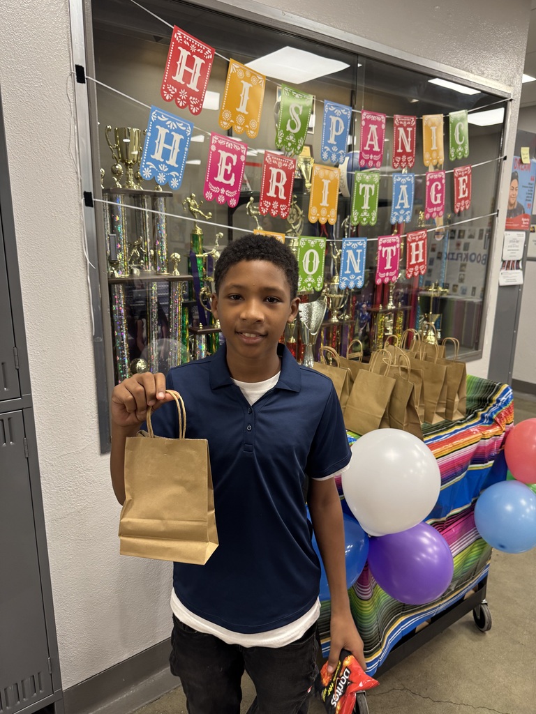 student in navy polo shirt holding up his goodie bag