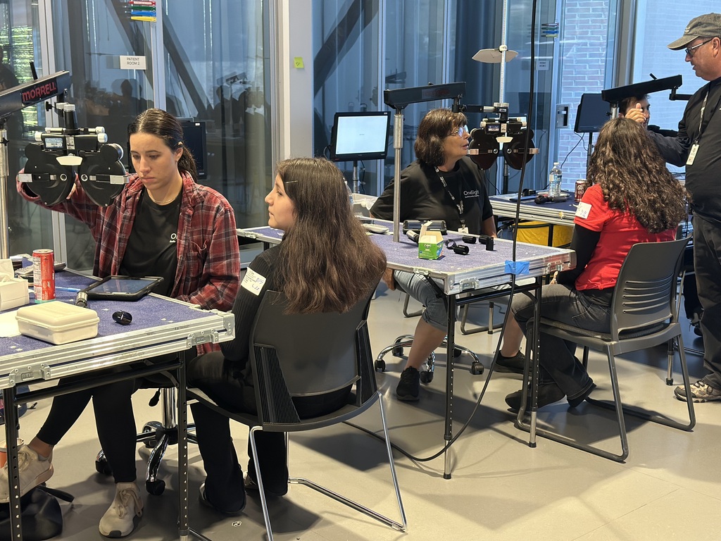 students sitting down in black chairs getting their vision checked