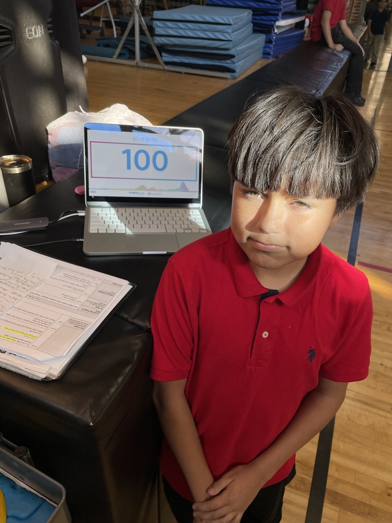 Gino wearing a red polo and posing in front of his 100 score PACER test