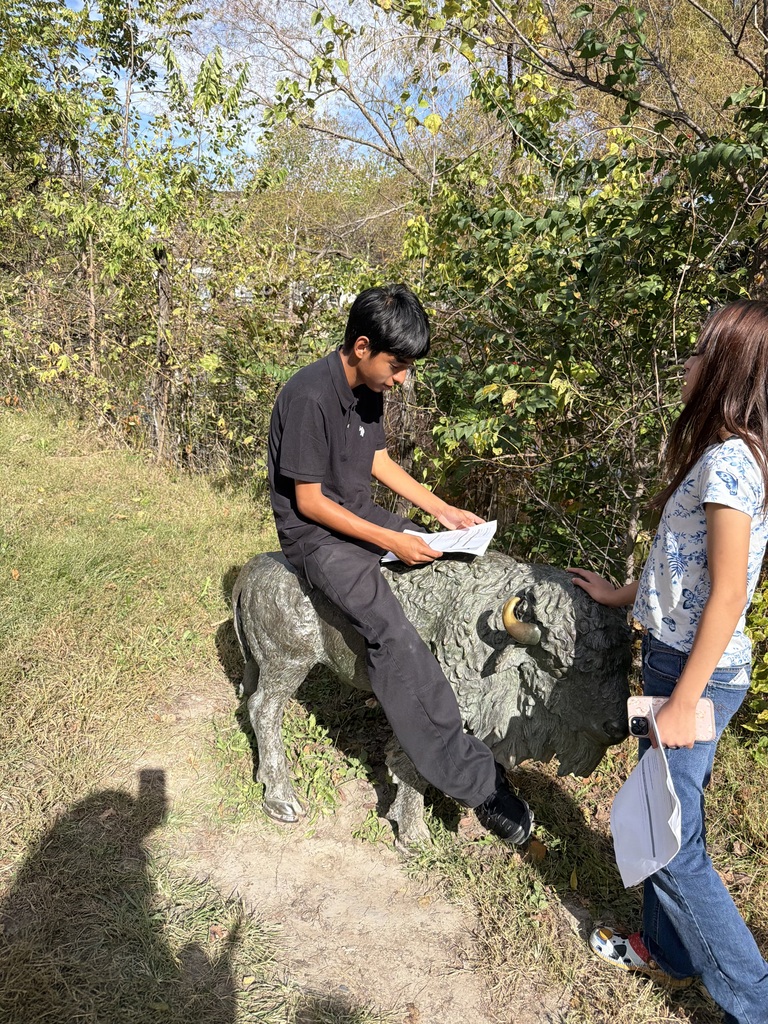 student dressed in black riding a plastic buffalo
