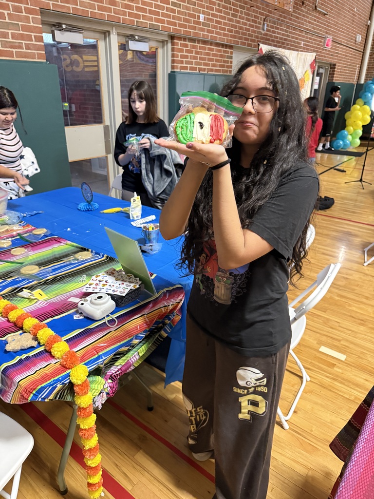 student wearing black, holding up a colorful concha