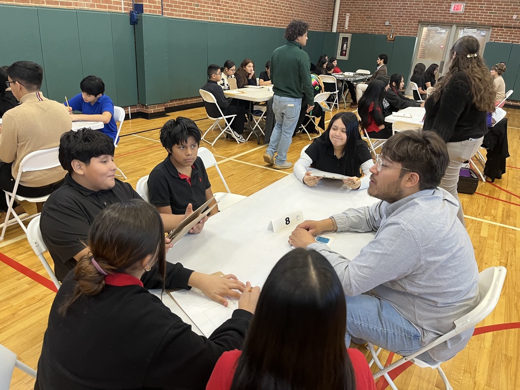students sitting at a white long table with a professional speaking about careers