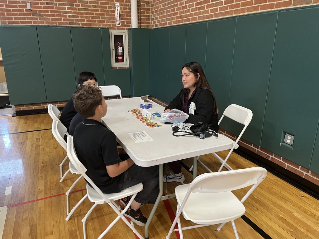 students sitting at a white long table with a professional speaking about careers