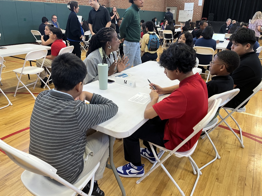 students sitting at a white long table with a professional speaking about careers