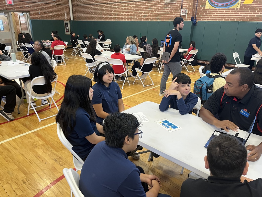 students sitting at a white long table with a professional speaking about careers