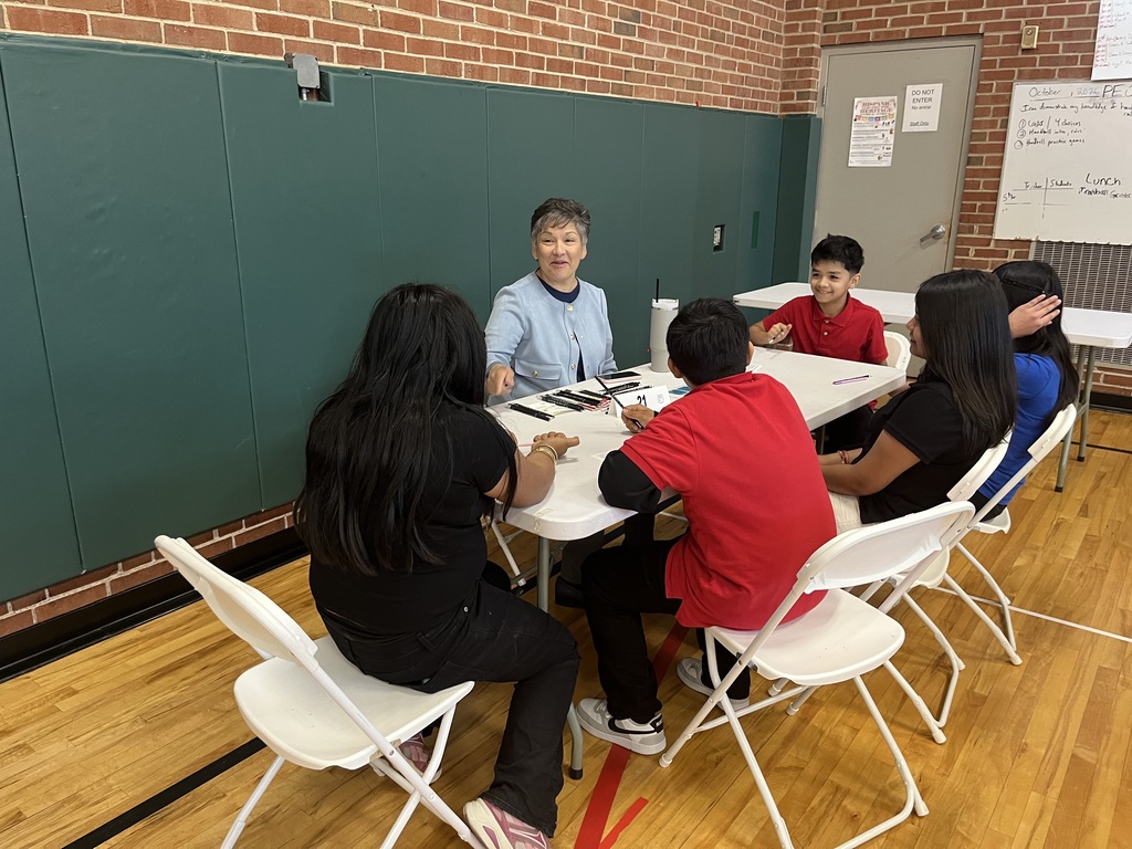 students sitting at a white long table with a professional speaking about careers