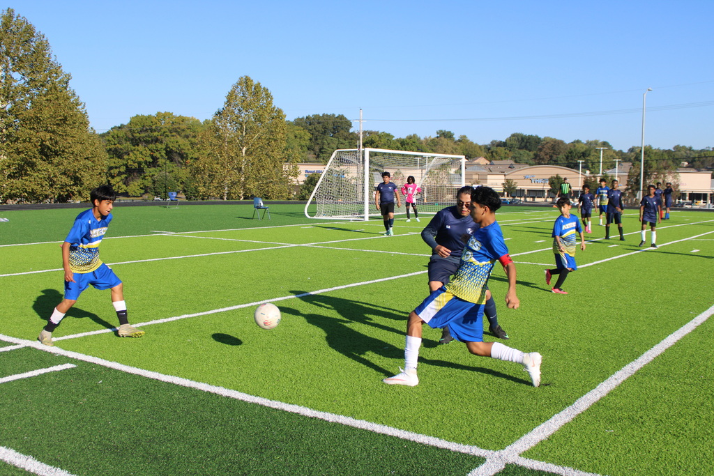 boys playing soccer on a very green field