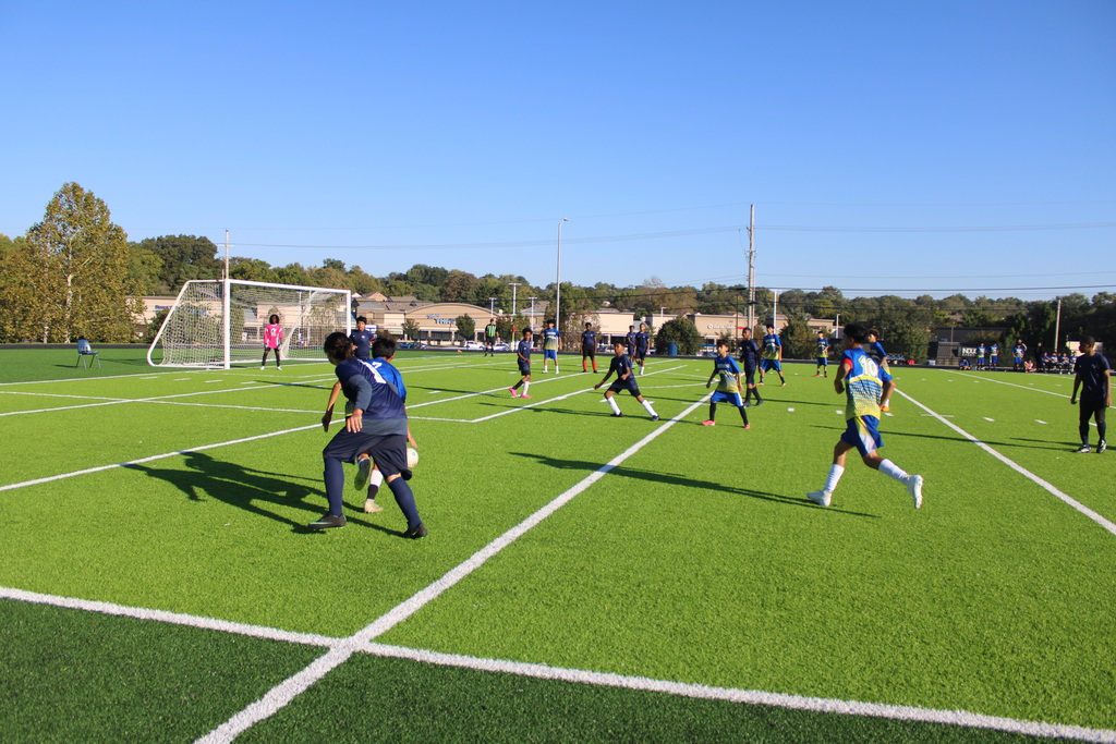 boys playing soccer on a very green field