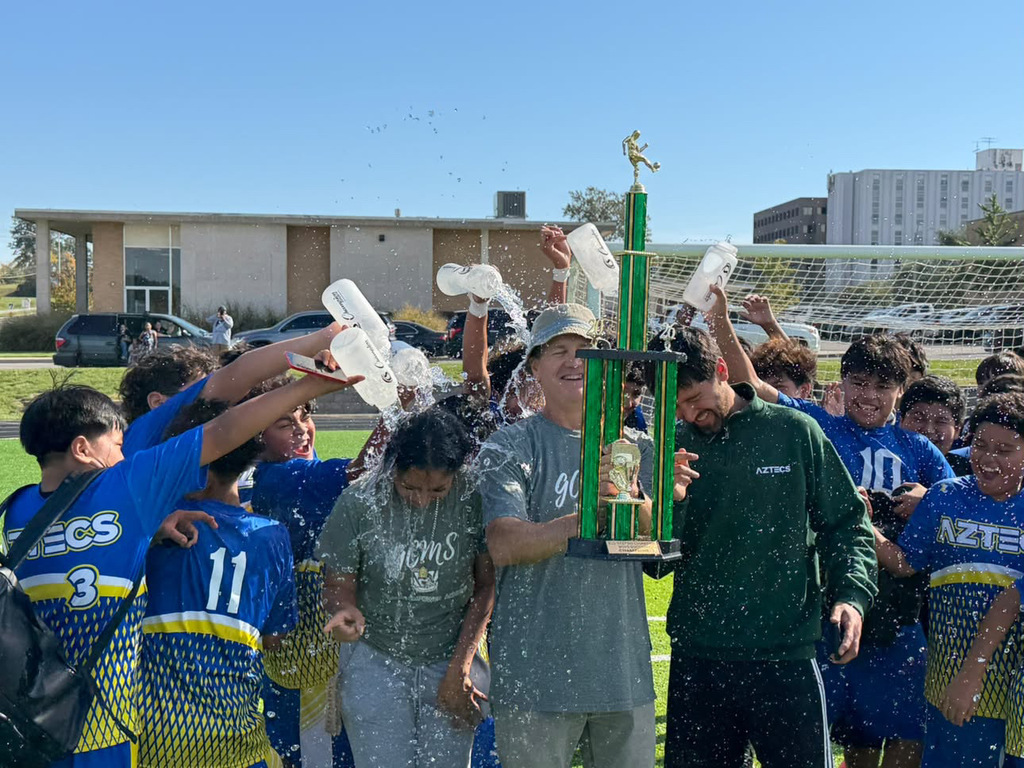 boys celebrating that they are champions and dumping water on their coaches