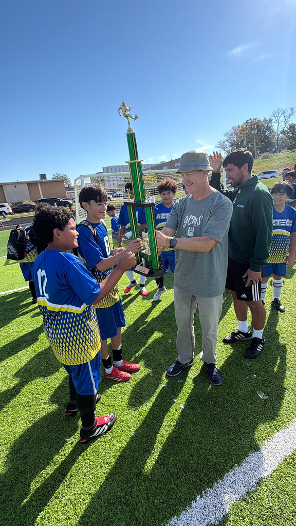 mr. c handing the trophy to one of the soccer players