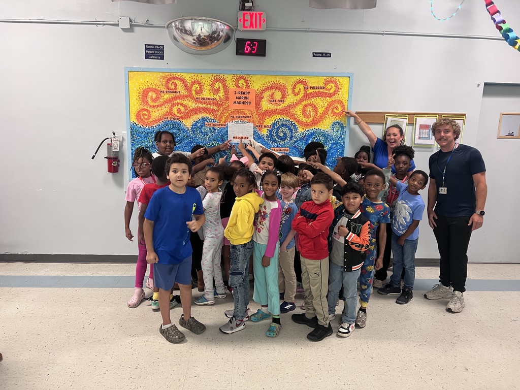 Ms. Miller's 2nd grade class pointing to the bulletin board that declares them the winner!