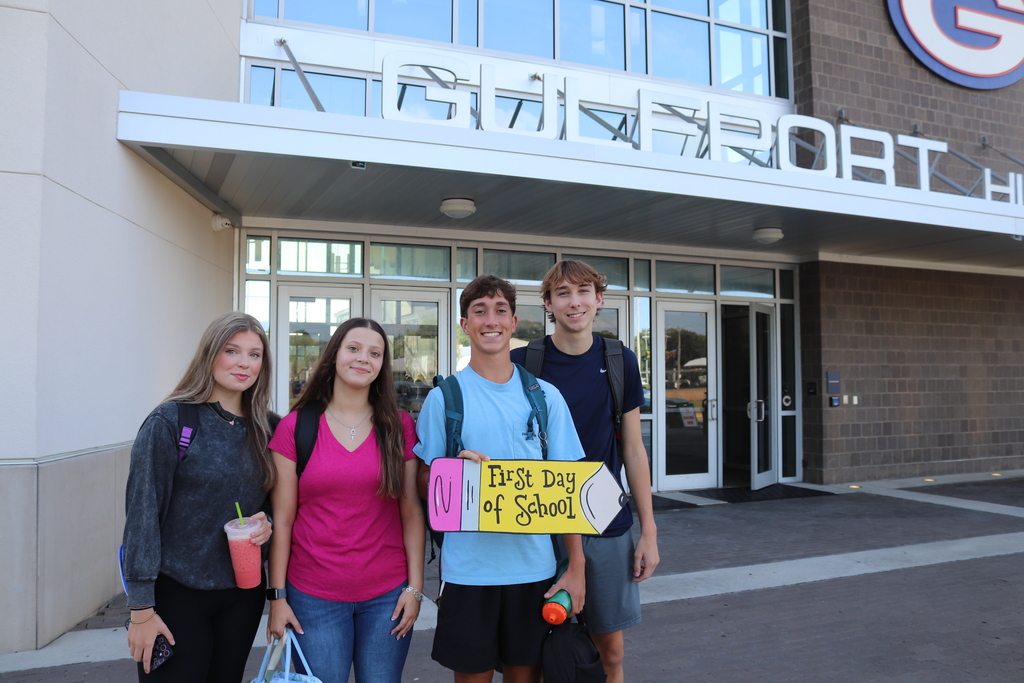 A group of students holding first day of school sign in front of Gulfport High School. 