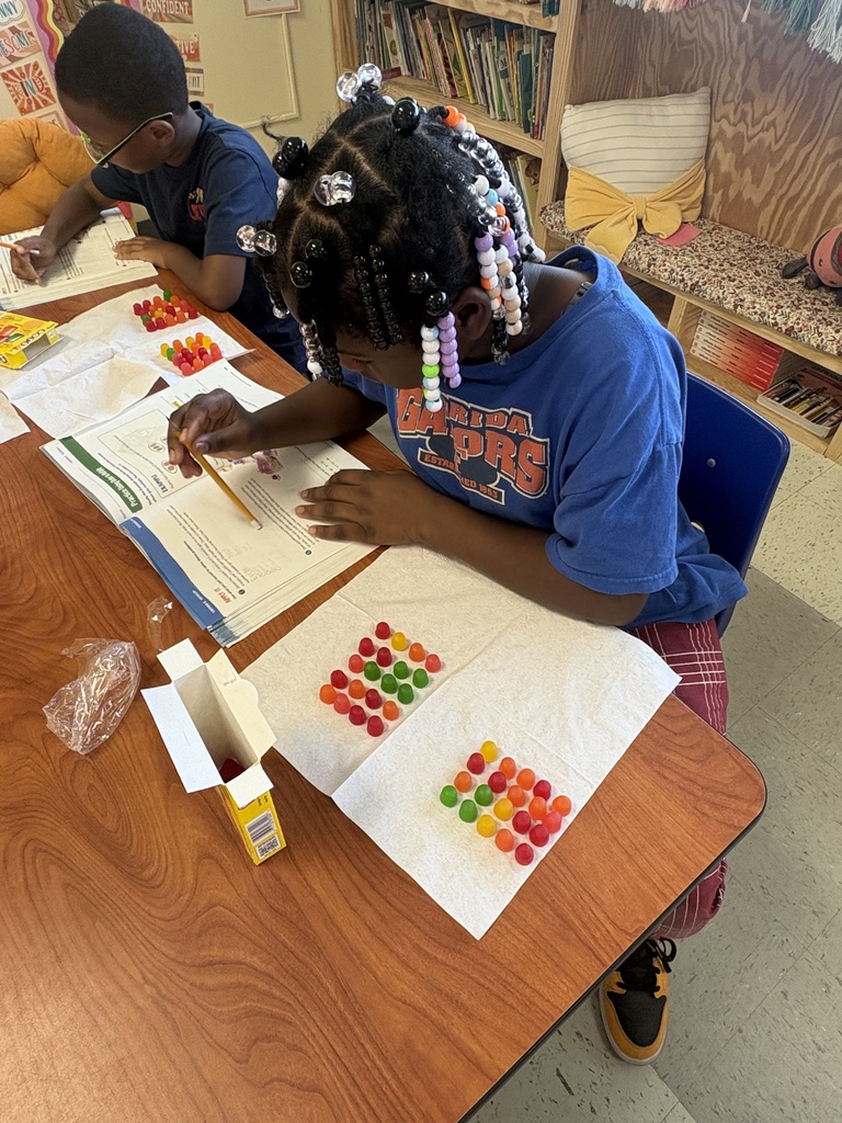 Two students building their arrays with Dots candy and writing their equations in their math book