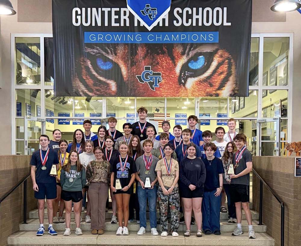 Students standing in front of a Gunter High School banner holding academic awards for UIL.