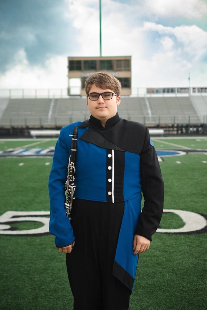 Justin Grayard  standing on the football field holding his Bass Clarinet.