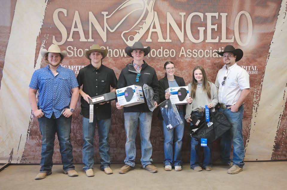 Six people pose with prizes in front of a wall with "San Angelo" and "Rodeo Association" banners.