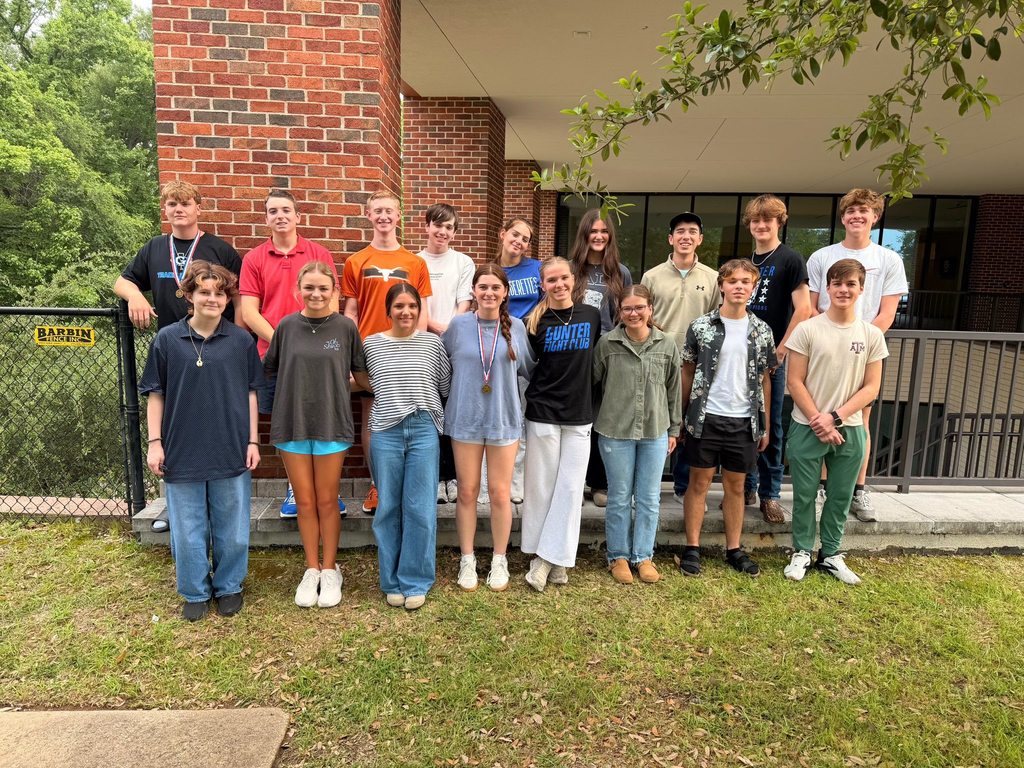 A group of students stands in front of a brick building, posing for a photo.