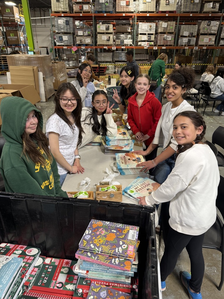 middle school students stand around a table with books