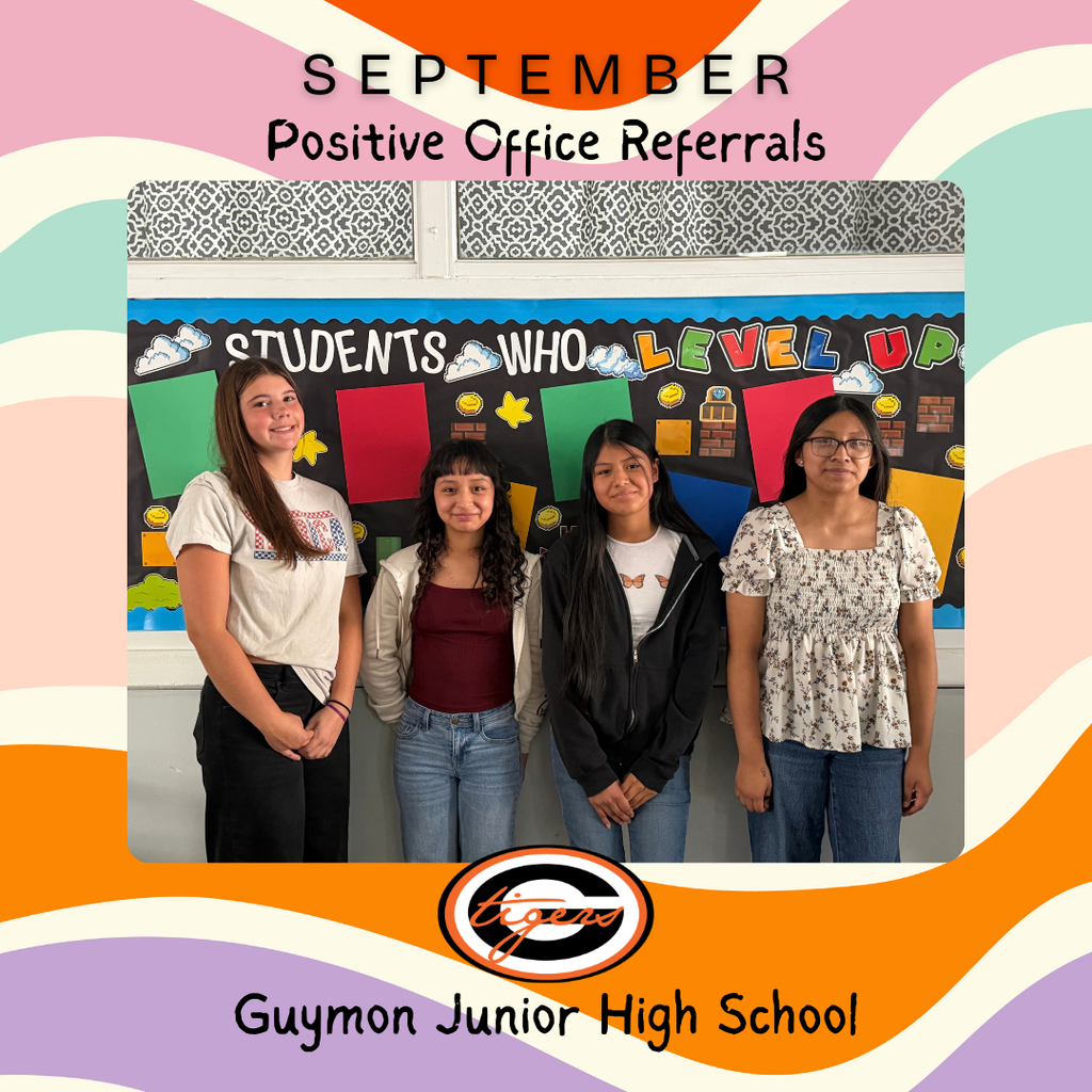 Five girls stand together, smiling, in front of a bulletin board with colorful art.