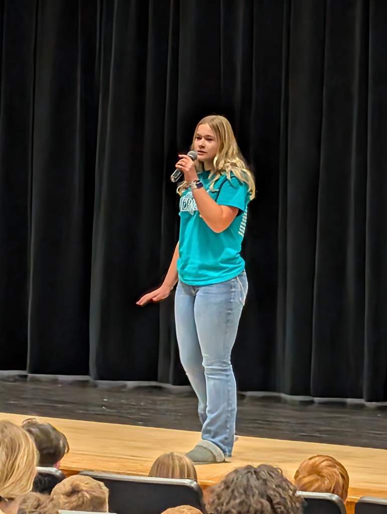 One student standing and singing on stage