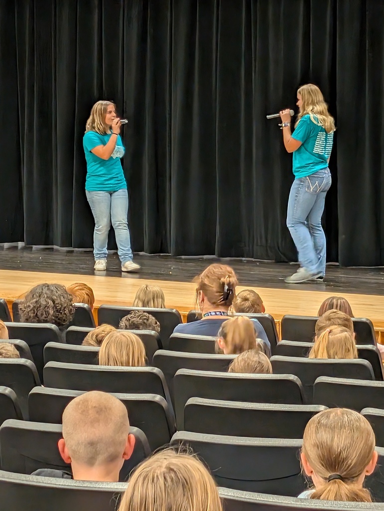 Two students standing and singing on stage