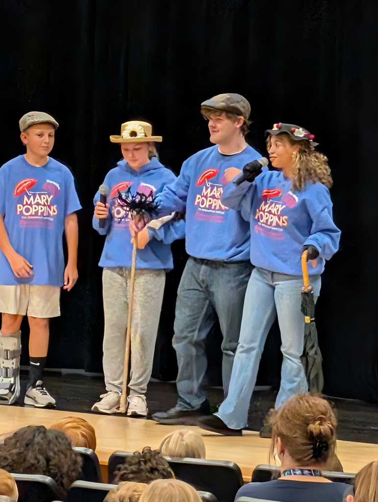 Four students standing and singing on stage