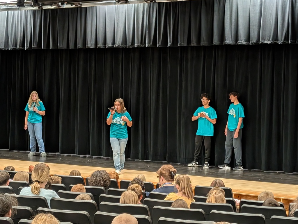 Four students standing and singing on stage
