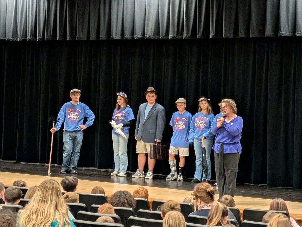 Six students standing and singing on stage