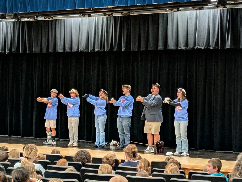 Six students standing and singing on stage