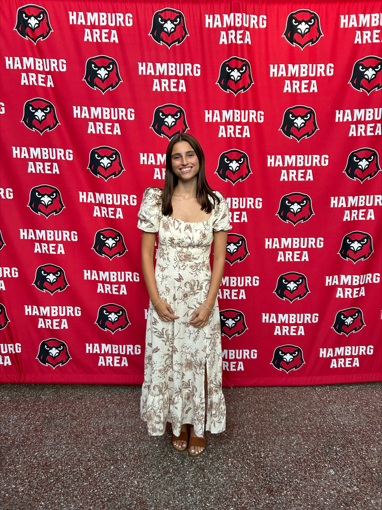 Daniella Young wearing a full length dress and bracelets on either hand, smiling with her hands at her sides.