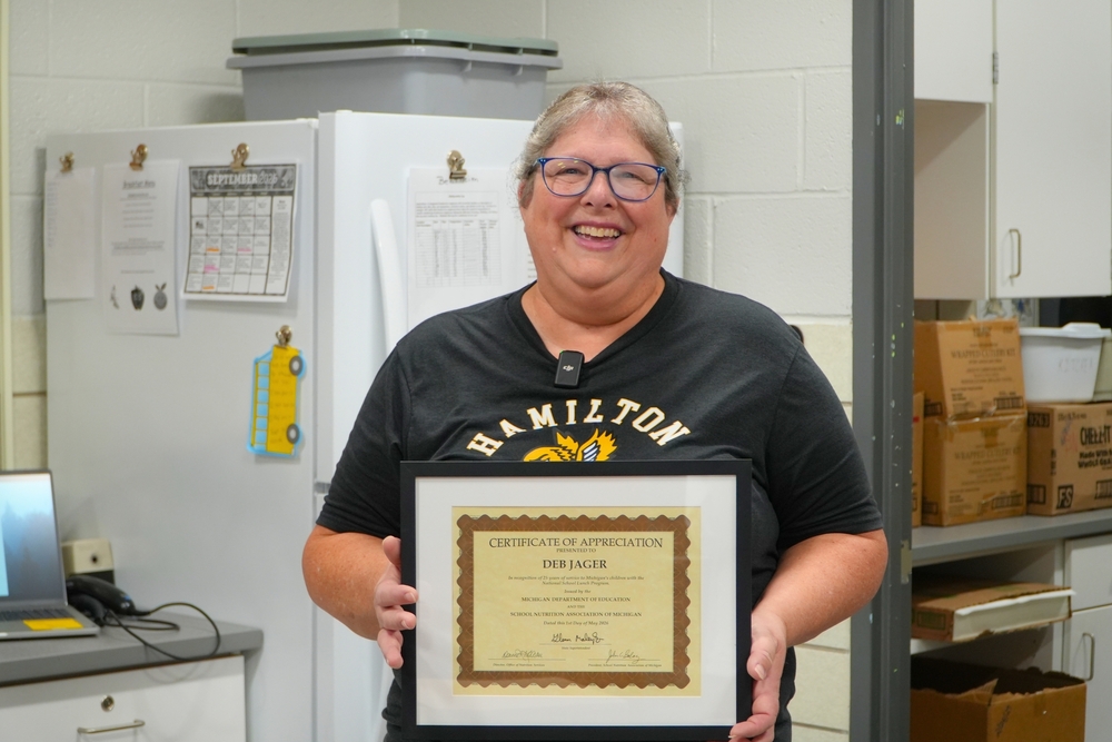 Deb Jager smiles and holds a certificate of appreciation.