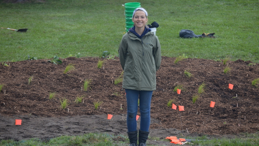 Alyssa Franck stands in front of a rain garden she created at Blue Star Elementary.